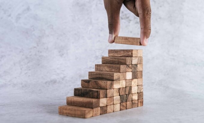 Stacking wooden blocks is at risk in creating business growth ideas.